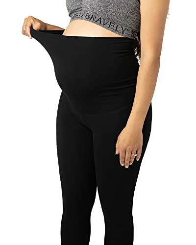 Pregnant woman wearing black maternity leggings.