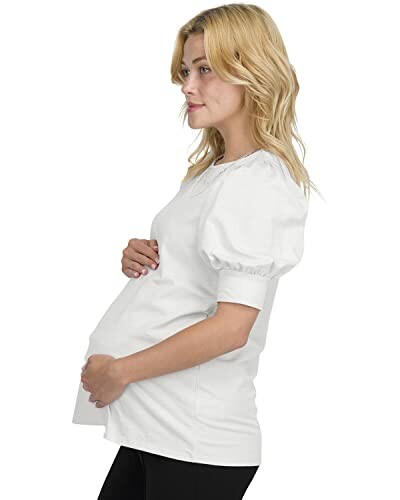 Pregnant woman in a white shirt holding her belly.