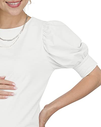 Woman in white puff sleeve top with a necklace.