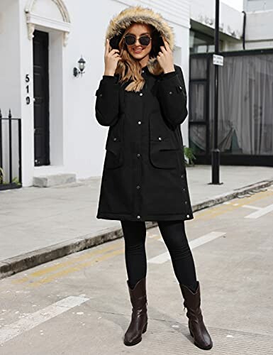 Woman in black coat with fur hood standing on street