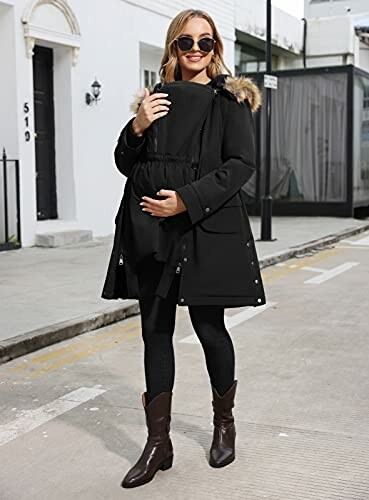 Woman in a black coat with fur hood, standing on a city street.