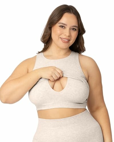 Woman in grey crop top lifting fabric slightly.