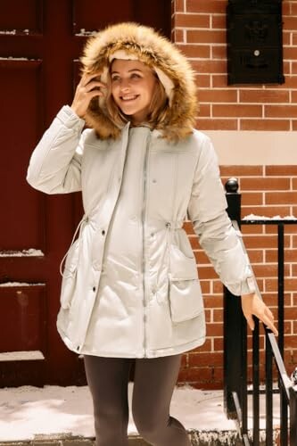 Smiling woman in a winter coat with fur hood in a snowy setting